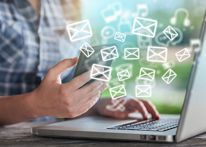 person checking email on computer and phone