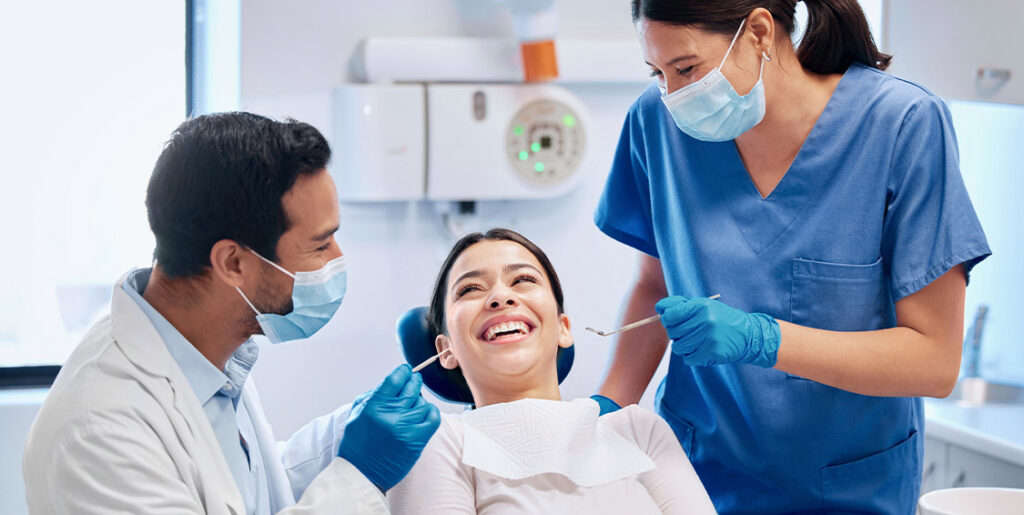 patient in dental chair with dentist and assistant