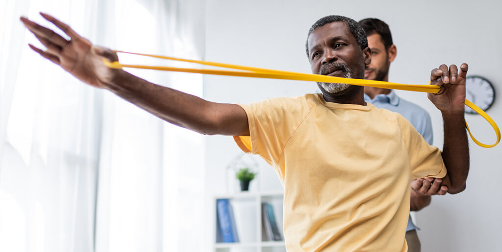 man using resistance band with physical therapist